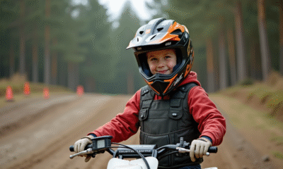 Jeune garçon en équipement de motocross debout près de son pit bike sur une piste poussiéreuse