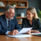 Deux professionnels souriants échangent des documents dans un bureau moderne